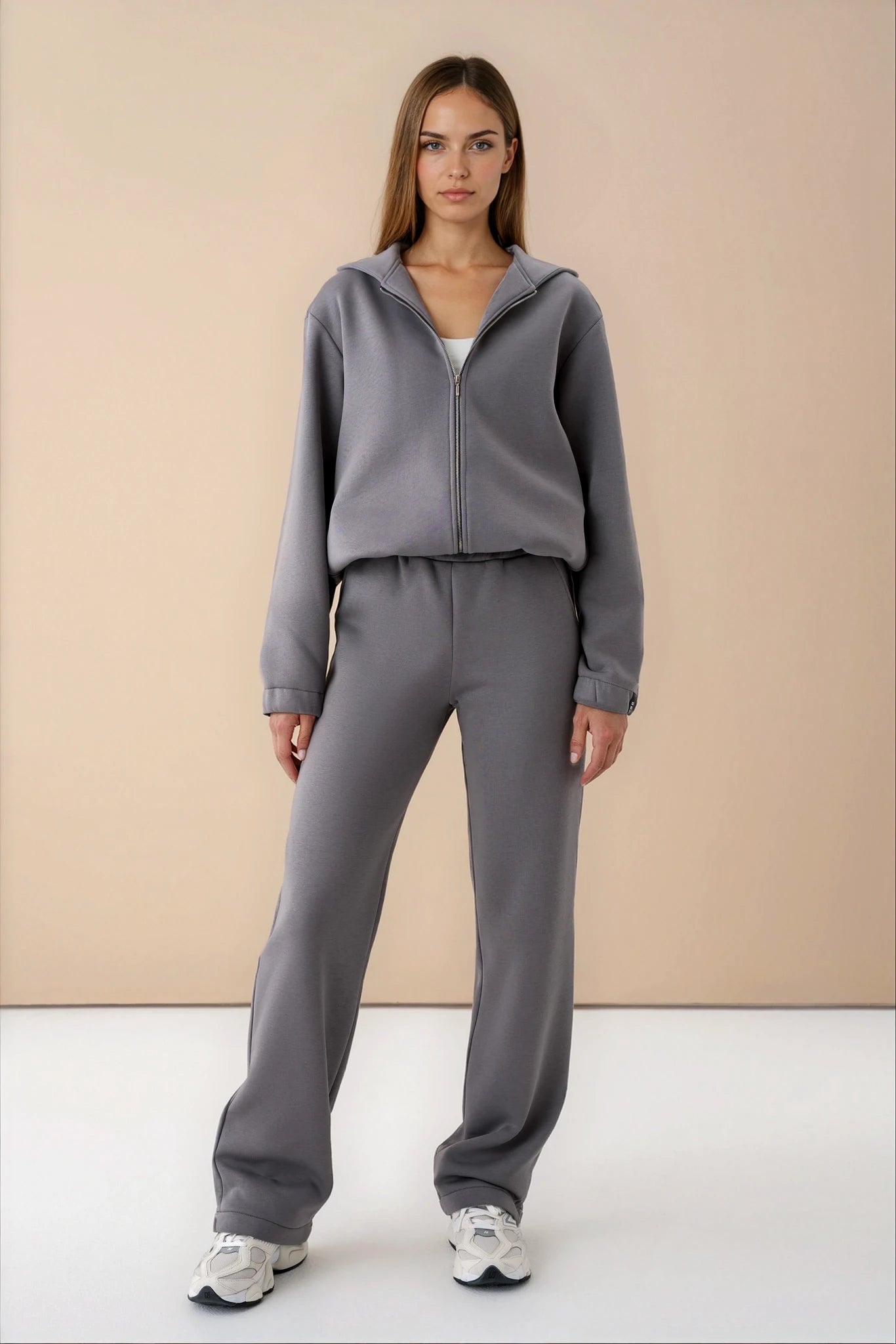 moteris vilki pilkos spalvos cutmyfashion treningus, stovi studijos fone, žiūri tiesiai į objektyvą