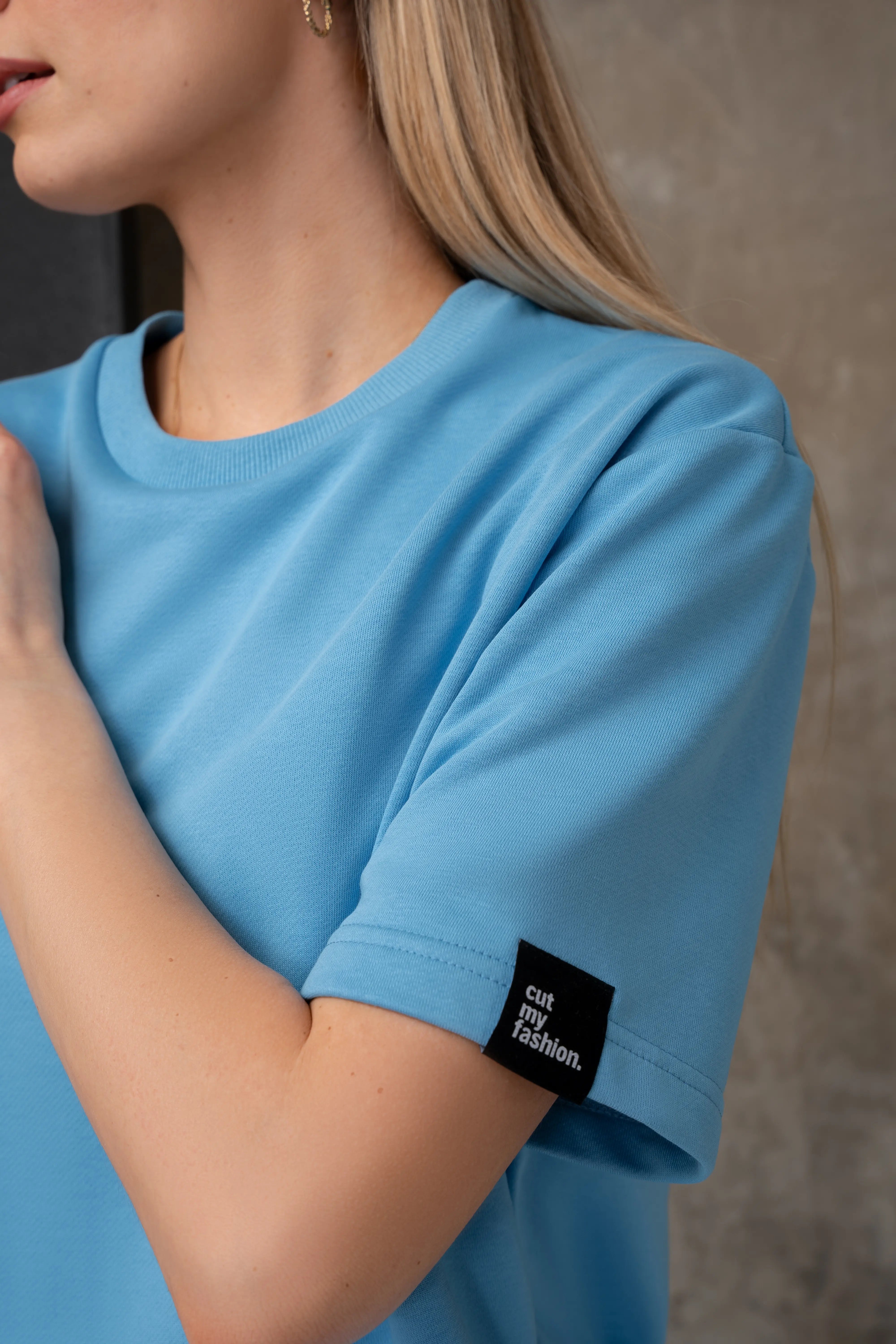 Žydros spalvos palaidinės rankovės detalė su „cutmyfashion“ logotipu