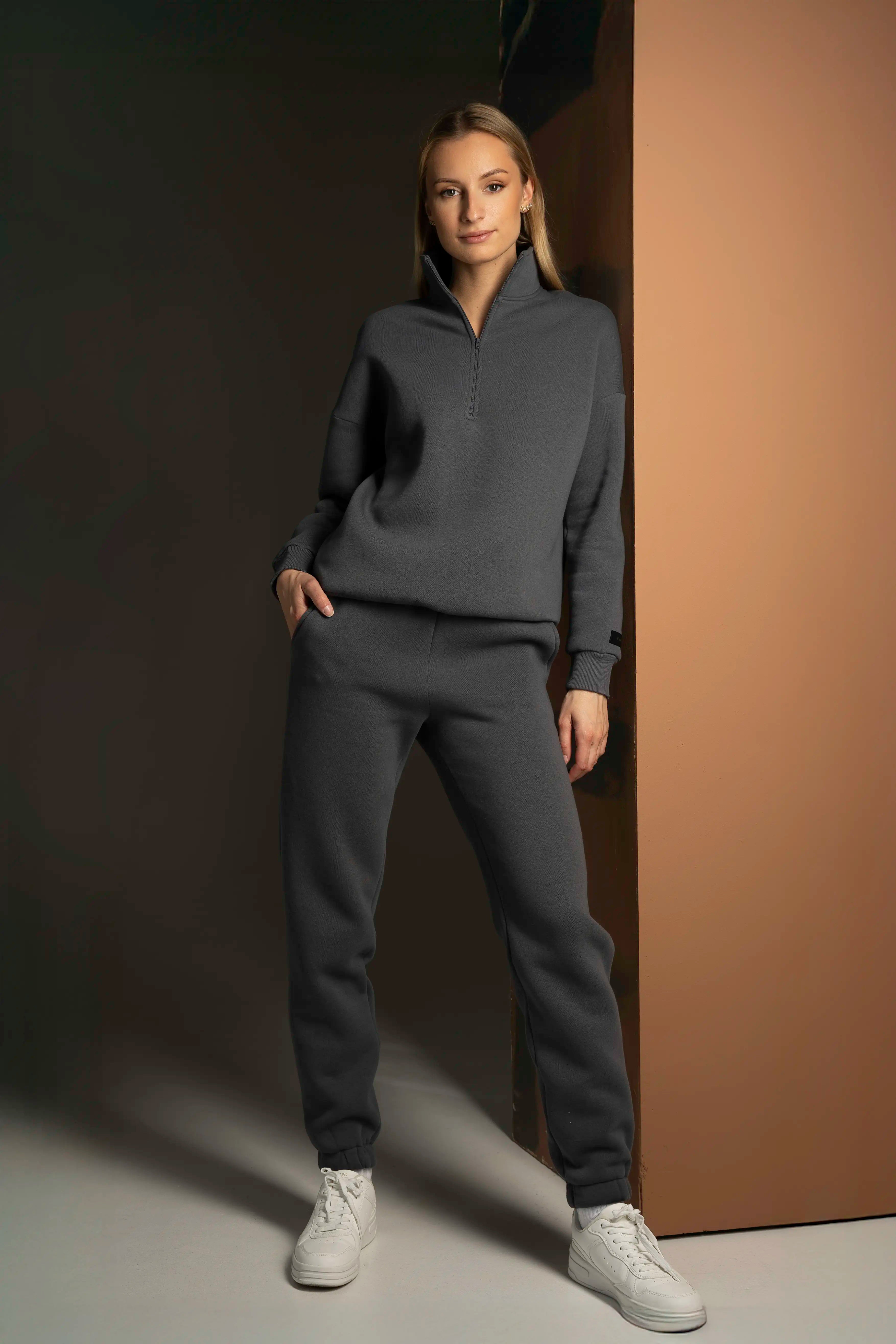 Moteris dėvi cutmyfashion pilkus laisvalaikio treningus. Universalus stilius, tinkantys kasdieniniams poreikiams.