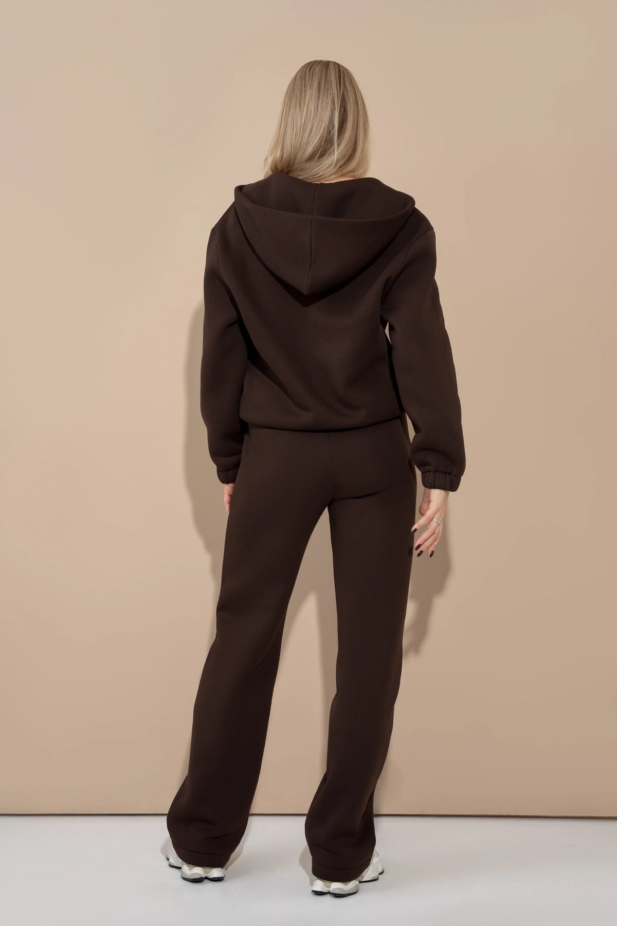 Brown women’s casual tracksuit from the back with a hood, loose sleeves, and straight-cut trousers