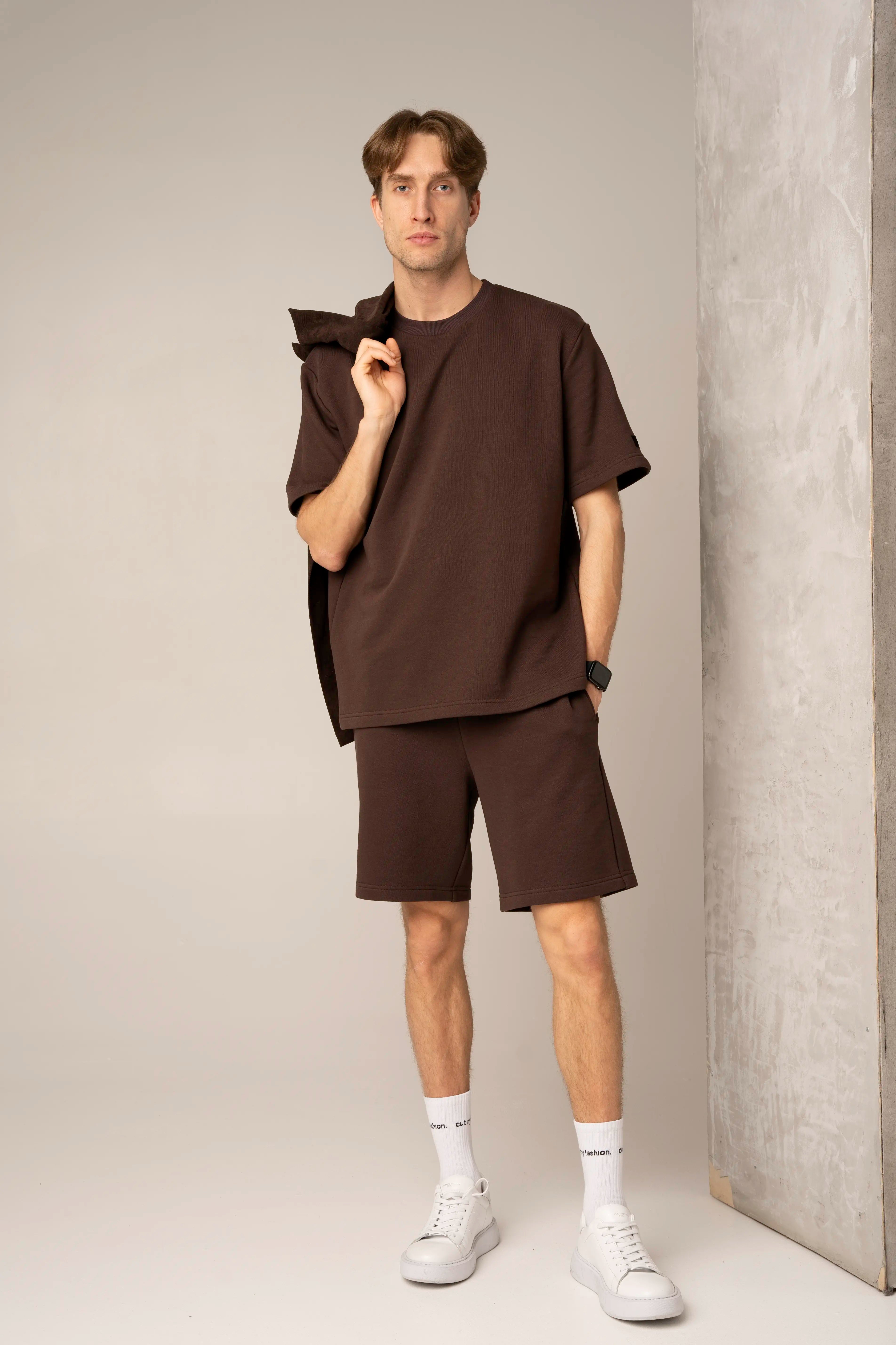 Rudos spalvos vyriškas laisvalaikio treningas su marškinėliais ir šortais, šortai su kišenėmis ir elastingu juosmeniu, ant peties laikomas džemperis