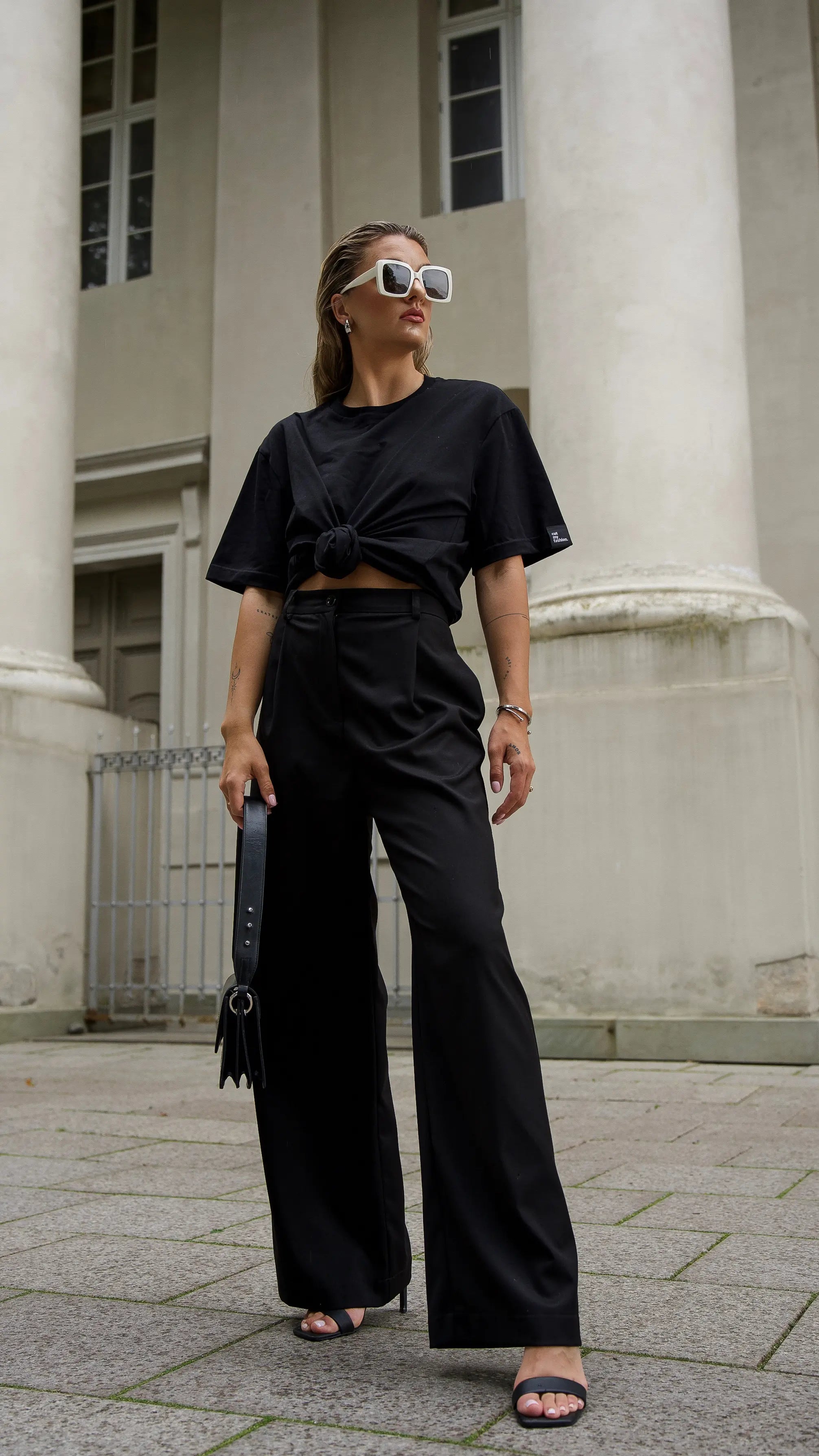Mergina dėvi juodus cutmyfashion oversized stiliaus laisvalaikio marškinėlius ir juodas platėjančias klasikines kelnes