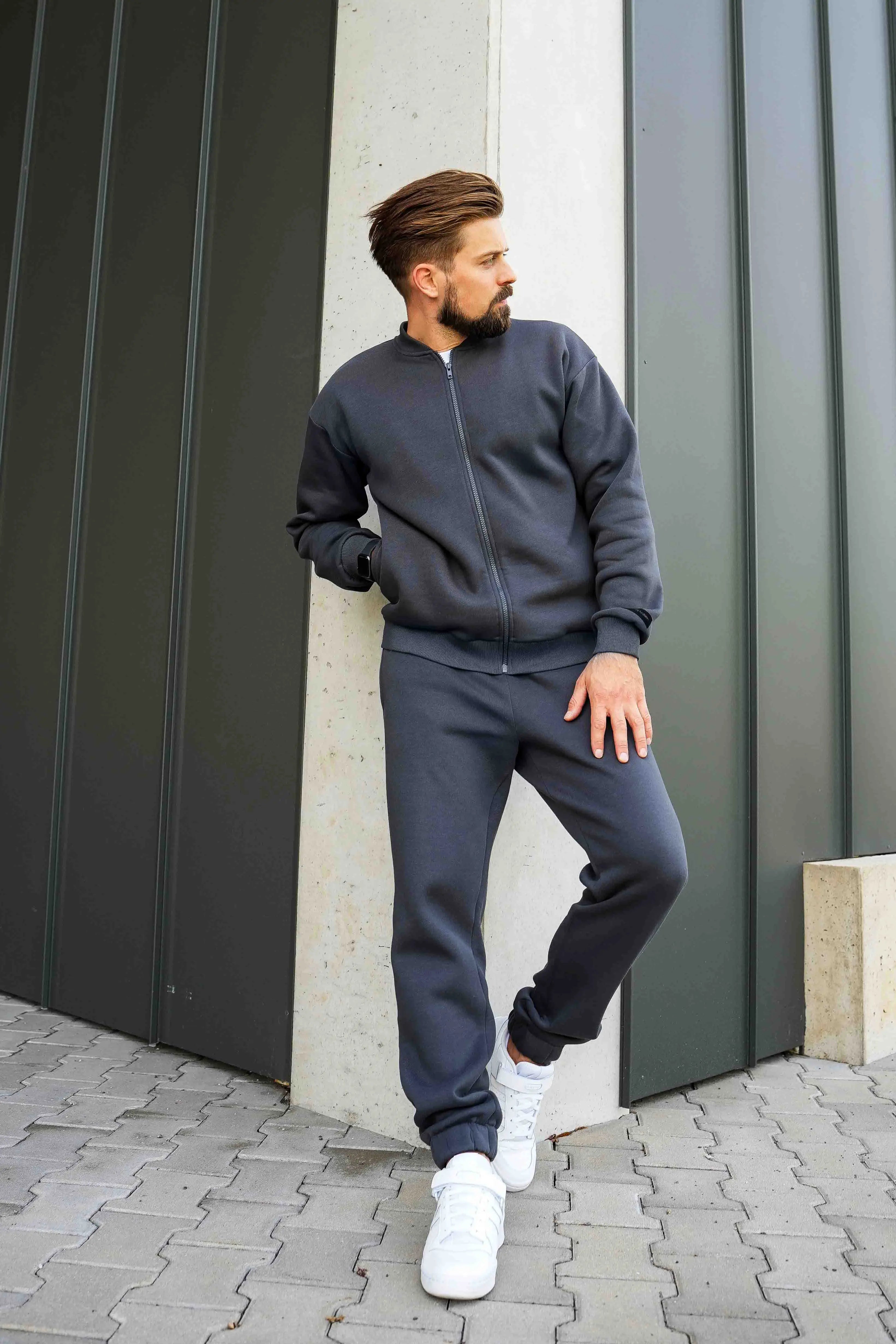 vyras vilki tamsius cutmyfashion treningus, atsirėmęs į sieną, žiūri į šoną, miesto fone
