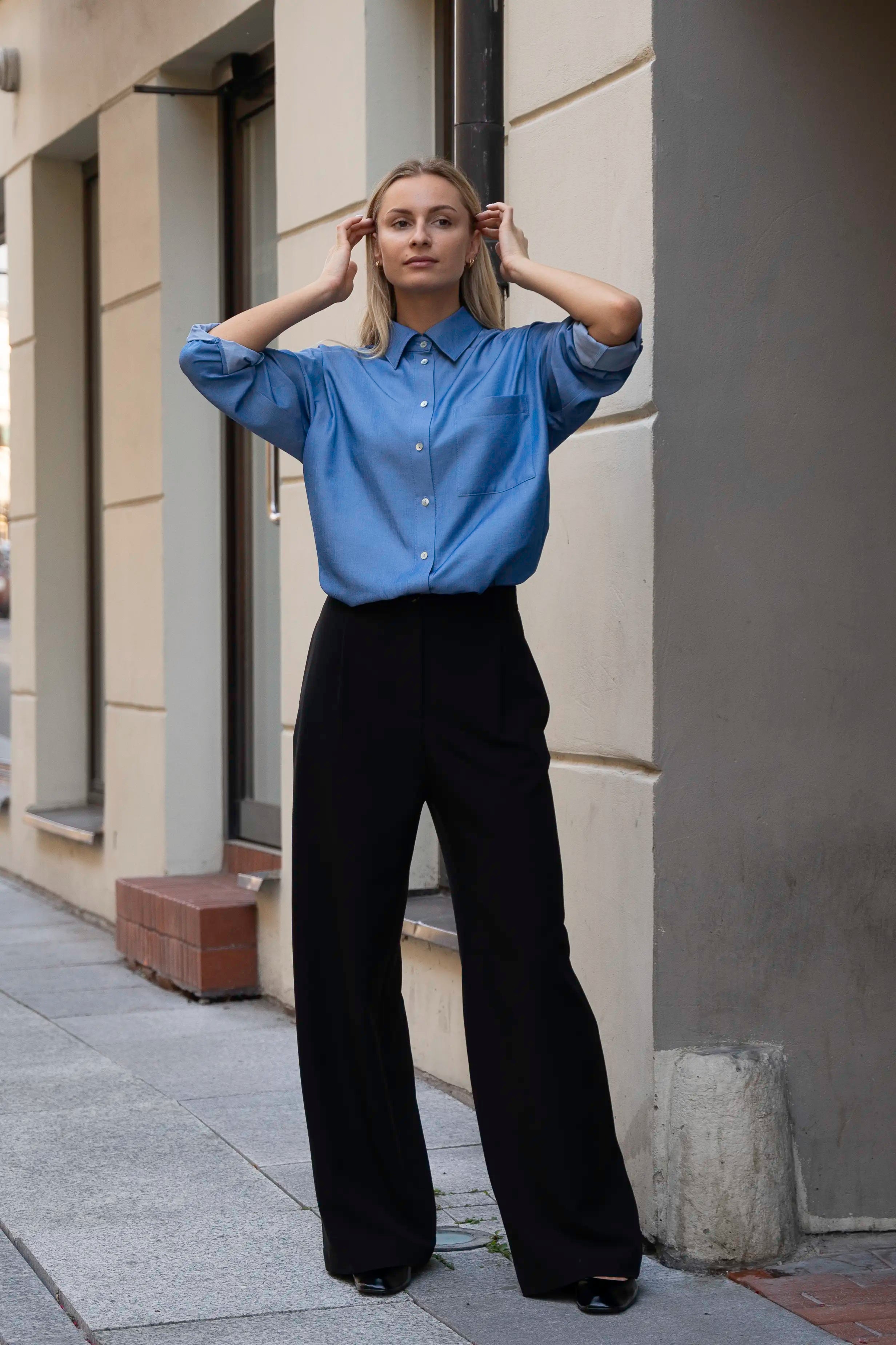 Women’s classic look with a blue shirt and black wide-leg trousers, front view outdoors