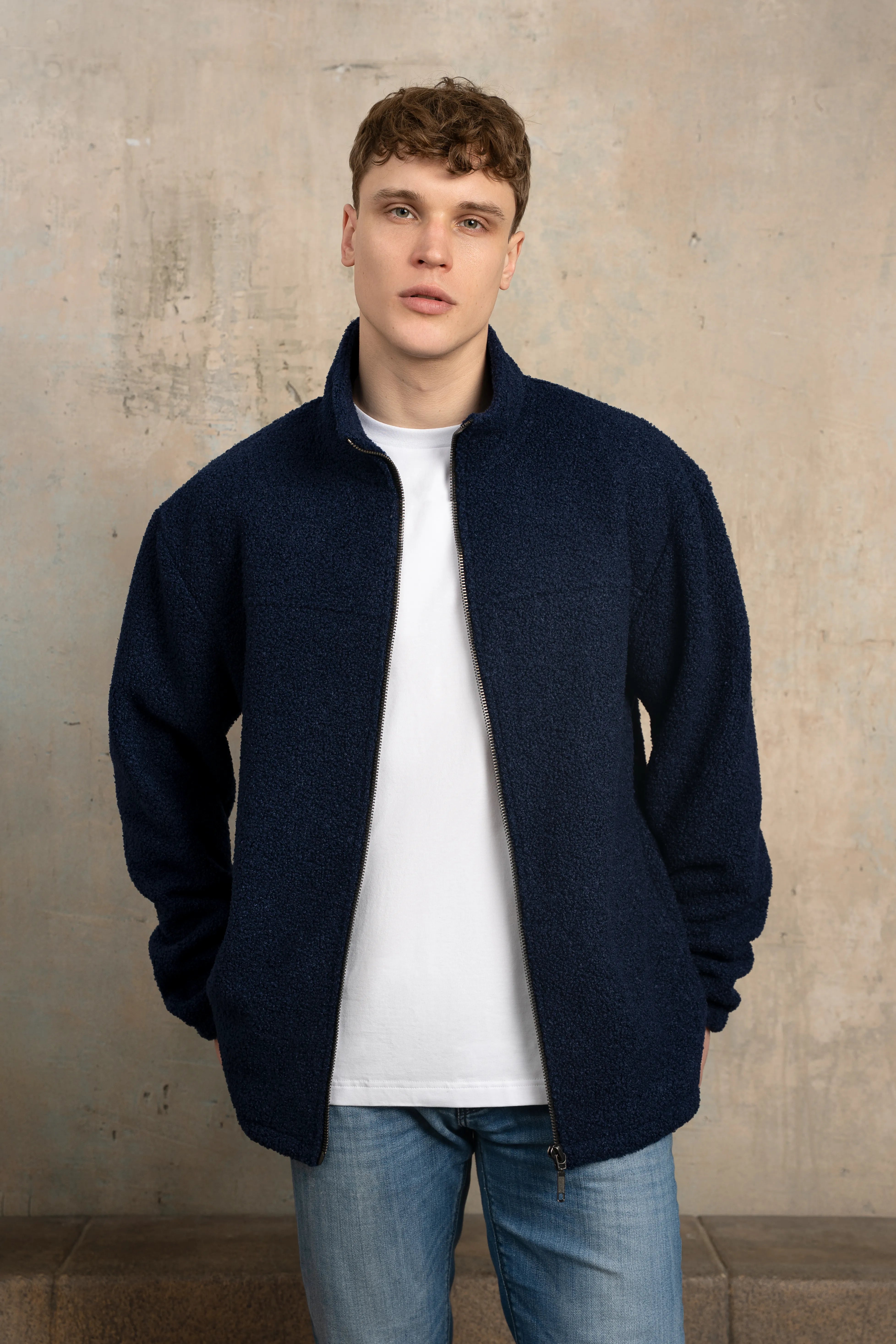 Tamsiai mėlynos spalvos vyriškas džemperis su pilno ilgio užtrauktuku, stačia apykakle, ilgomis rankovėmis ir laisvu siluetu