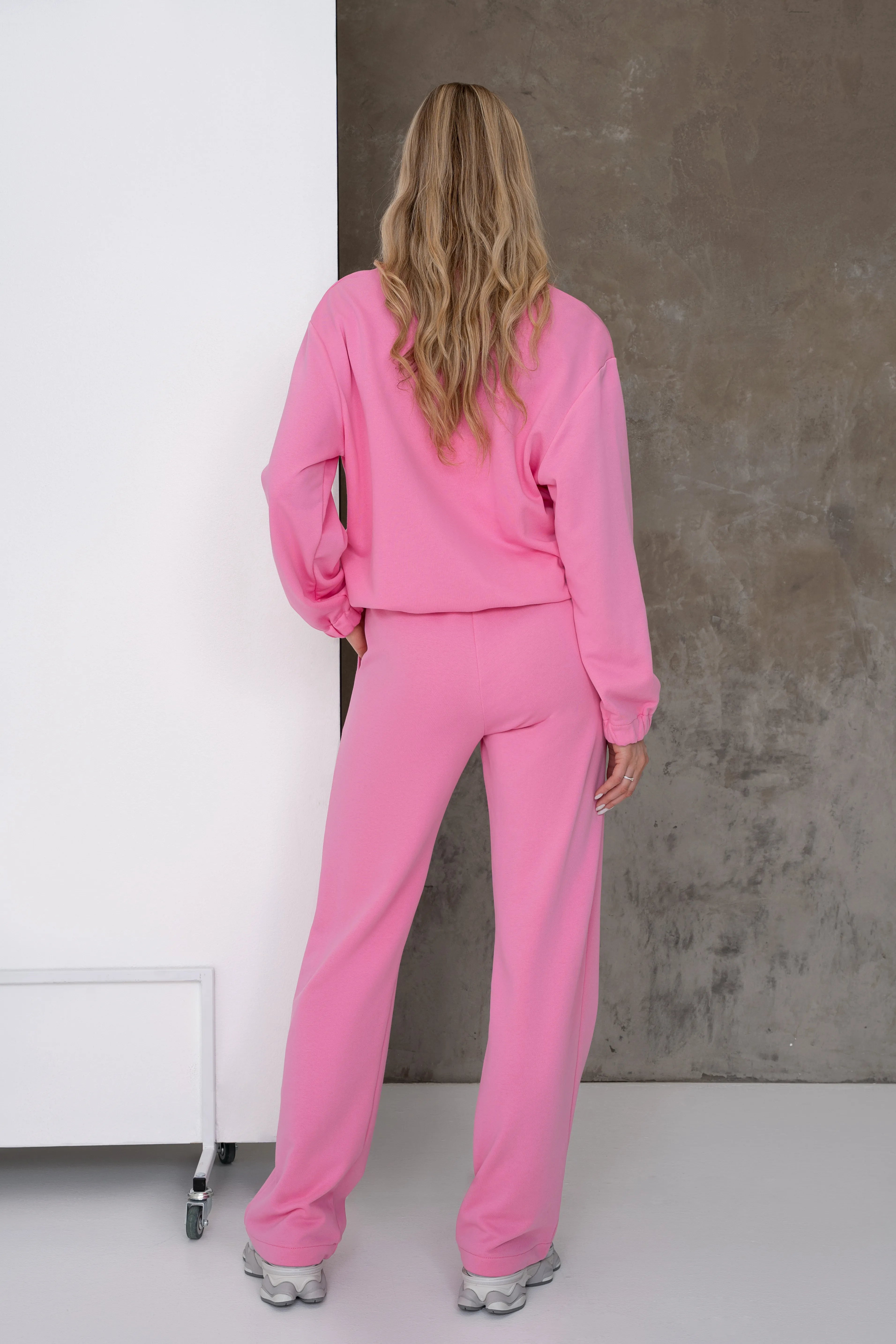 Pink women’s loungewear tracksuit with dropped shoulders, an adjustable drawstring at the hem of the sweatshirt, and straight loose-fit trousers, back view