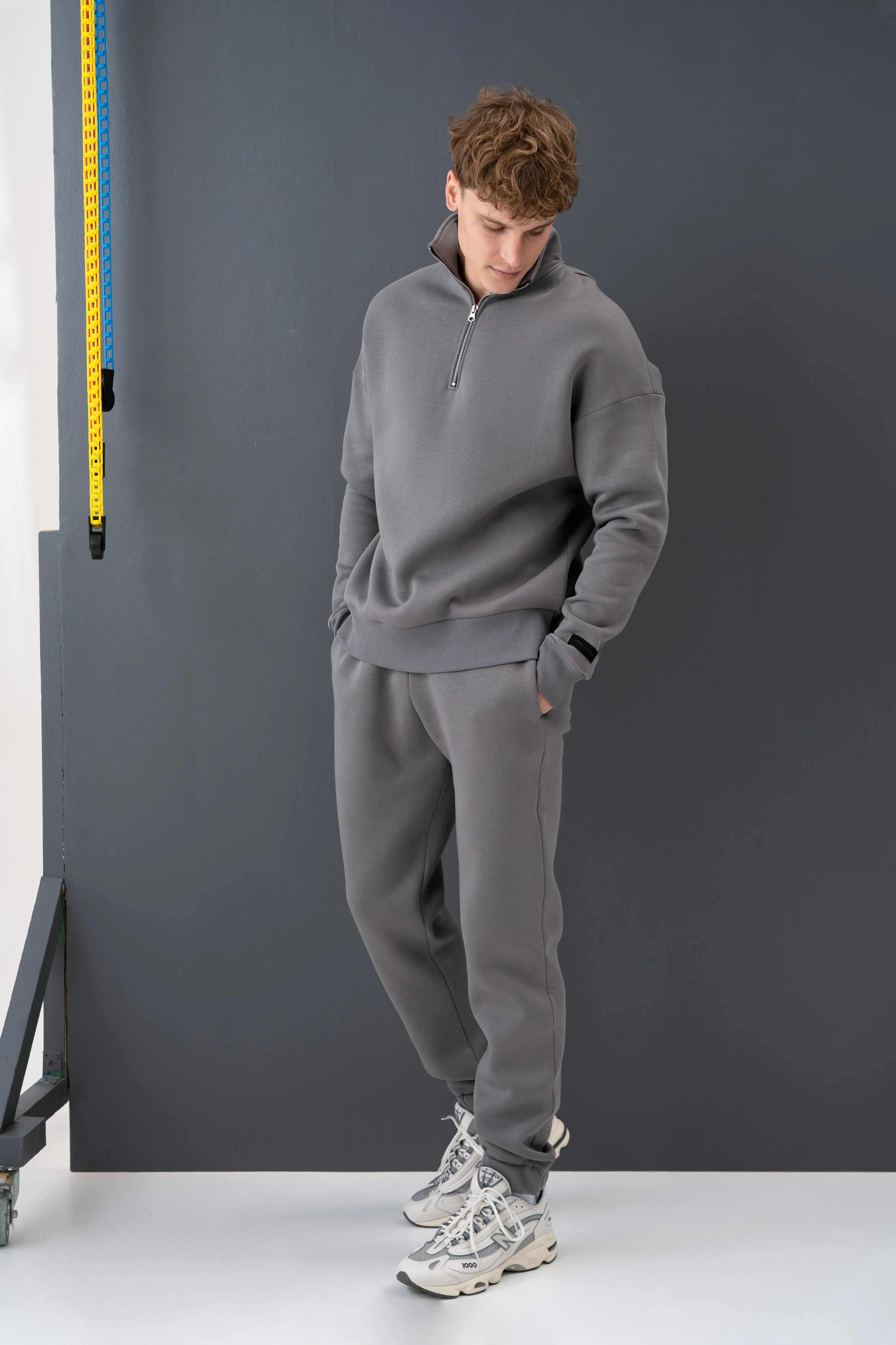 Pilkas vyriškas treningas su juodais raišteliais, puikiai tinkantis aktyviam gyvenimo būdui ir poilsiui namuose.