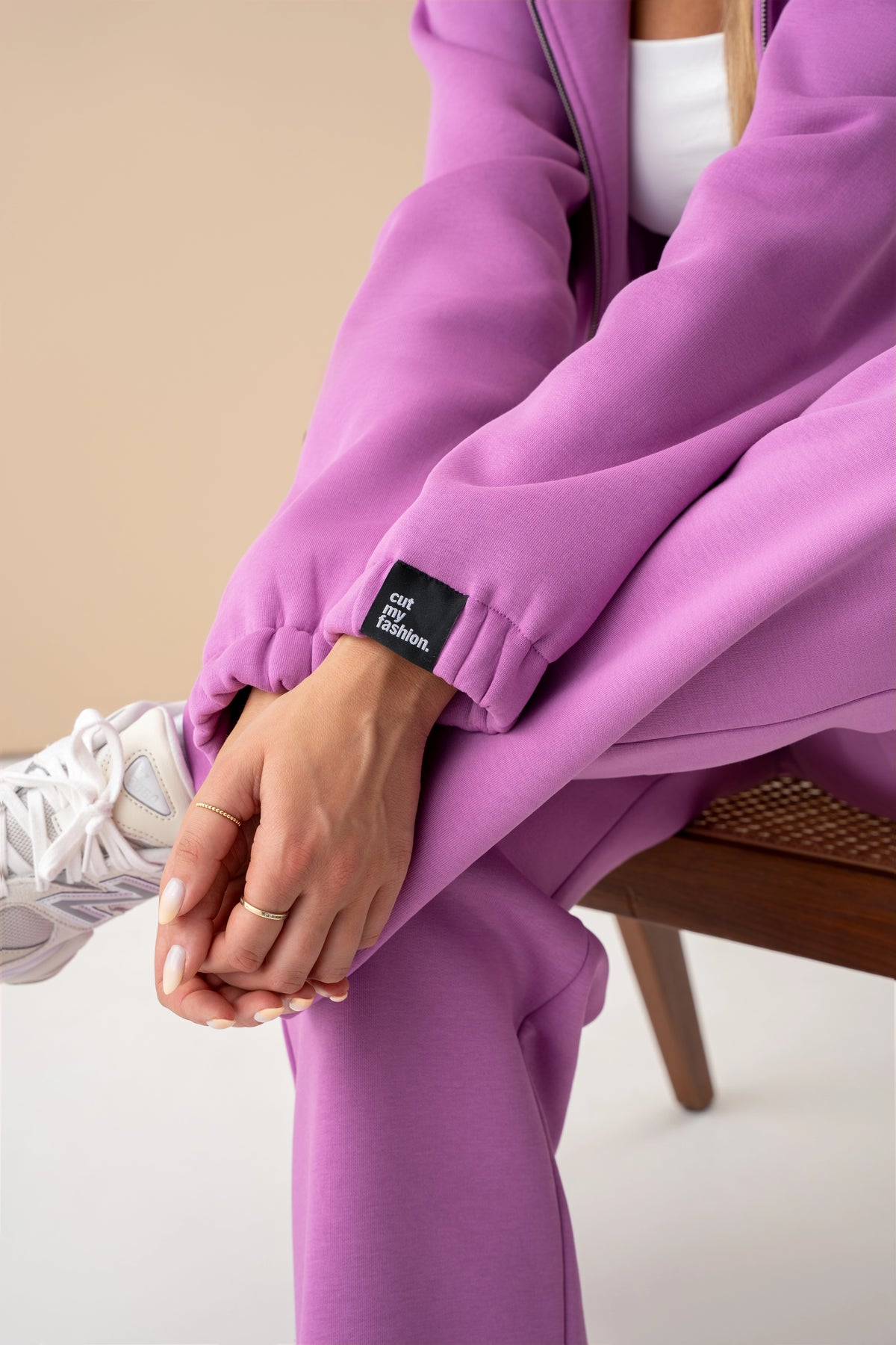 Close-up of a pastel pink cutmyfashion sleeve and white sneakers, the model is sitting on a chair