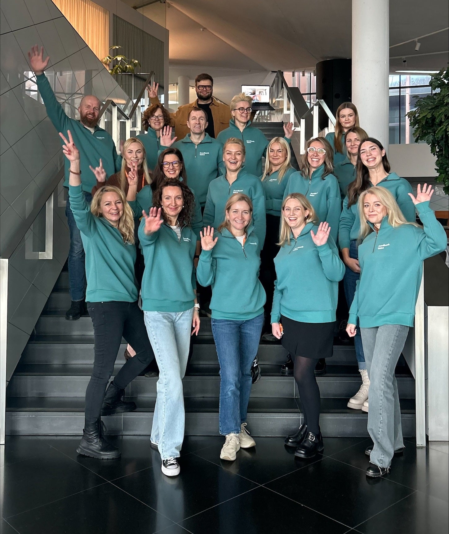 Banko darbuotojai pozuoja su naujais žalios spalvos laisvalaikio džemperiais, kuriuos pagamino cutmyfashion